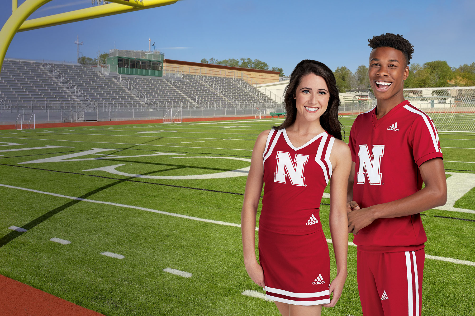 male and female cheerleaders on a football field wearing red custom adidas cheer uniforms
